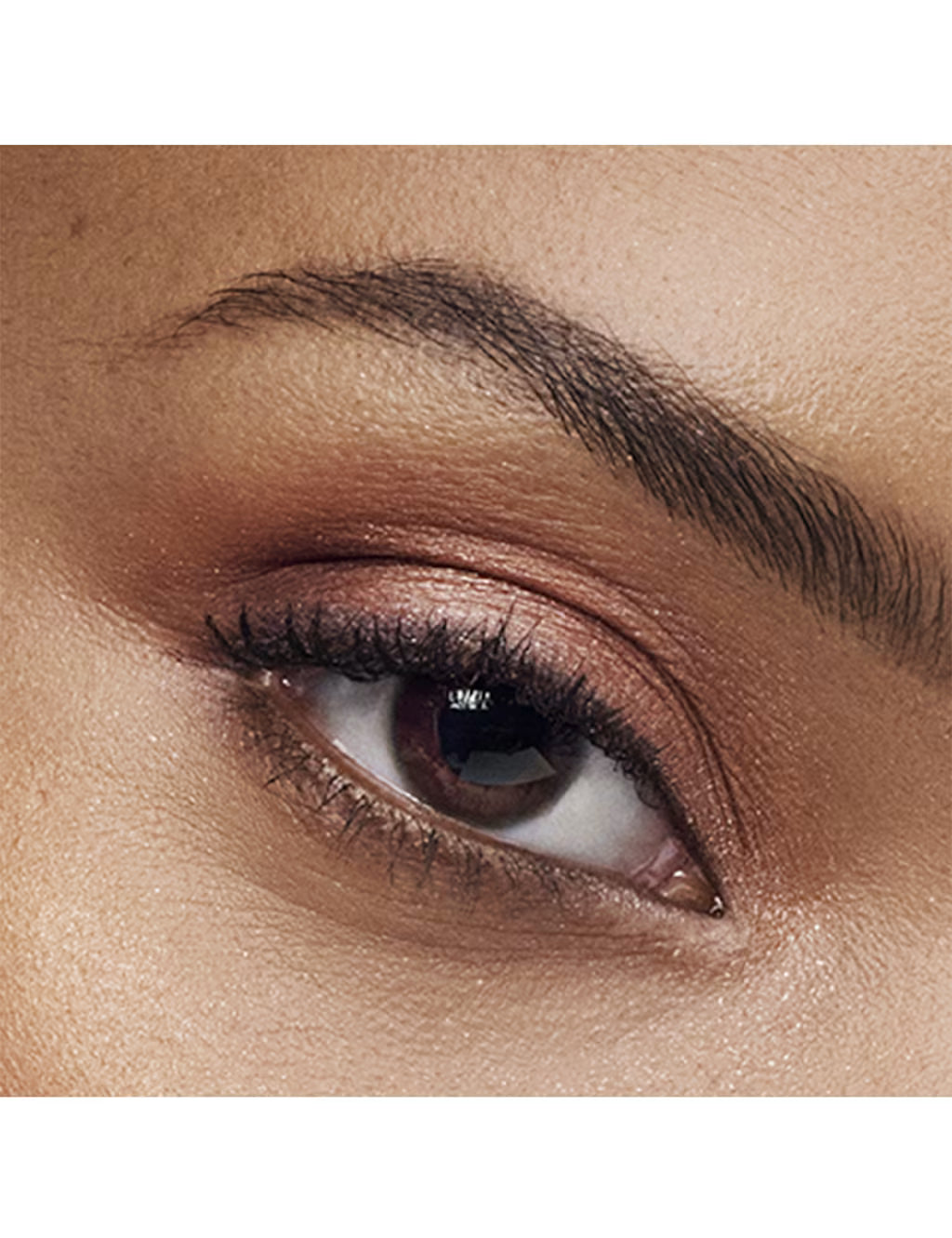 Close-up of a person's eye wearing a warm brown eyeshadow with a subtle shimmery finish and black eyeliner.